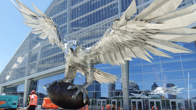 A giant stainless steel falcon is rising up in front of Mercedes-Benz Stadium